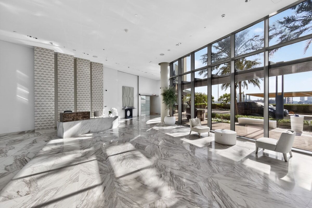 A spacious lobby with a marble floor, large windows, and modern furniture.