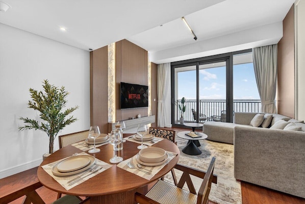 Un salon moderne avec un coin repas, un téléviseur à écran plat fixé au mur et un balcon avec vue.
