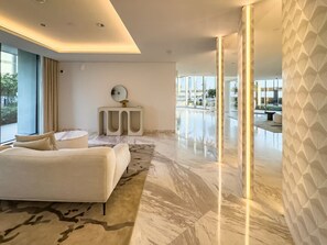 Una habitación de hotel moderna con una cama grande, una mesita auxiliar pequeña y vistas al exterior a través de amplias ventanas.