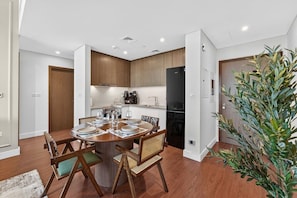 Une cuisine moderne avec des meubles en bois, une table à manger pour quatre personnes et un réfrigérateur.