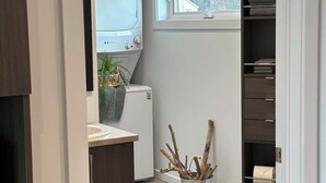 A modern kitchen with a built-in oven, a small sink, and a window with a view of greenery outside. - Complexe Étoile d'Or (Riviere à Claude)