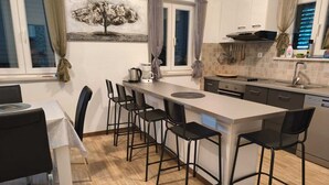 Eine moderne Küche mit Kochinsel, Barhocker und einem Esstisch mit Stühlen.
