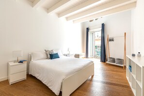 Ein Schlafzimmer mit Bett, Nachttischen, einem Kleiderschrank und einem Balkon mit Vorhängen.