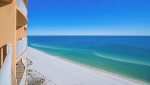 A beachfront hotel with a balcony overlooking a sandy beach and clear blue ocean. - Phoenix Orange Beach 1802 Relax in Style (Orange Beach)
