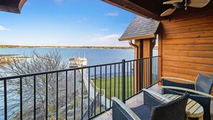 Eine Holzterrasse mit Korbmöbeln mit Blick auf einen See und eine Anlegestelle mit Boot.