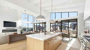 A modern kitchen with a central island, large windows, and a dining area with a view. - Lake Luxury- Juniper Ridge-Pool Table and Beautiful Decor (Graford)