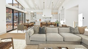 A modern living room with a large sectional sofa, a dining area, and a kitchen in the background. - Lake Luxury- Juniper Ridge-Pool Table and Beautiful Decor (Graford)