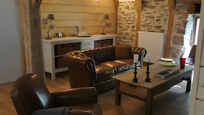 Un salon chaleureux avec un canapé en cuir, une table basse en bois et un meuble blanc.