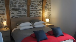 Een bed met kussens, een nachtkastje met een lamp, en een stenen muur.