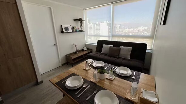 A modern living room with a dining area set for four. - Family-Friendly Apartment • Walk to Parks & Shops • Safe and comfort for all. (Santiago)