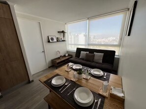 A modern living room with a dining area set for four. - Family-Friendly Apartment • Walk to Parks & Shops • Safe and comfort for all. (Santiago)