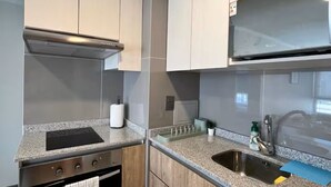 A modern kitchen with a stainless steel sink, a built-in oven, and wooden cabinets. - Family-Friendly Apartment • Walk to Parks & Shops • Safe and comfort for all. (Santiago)