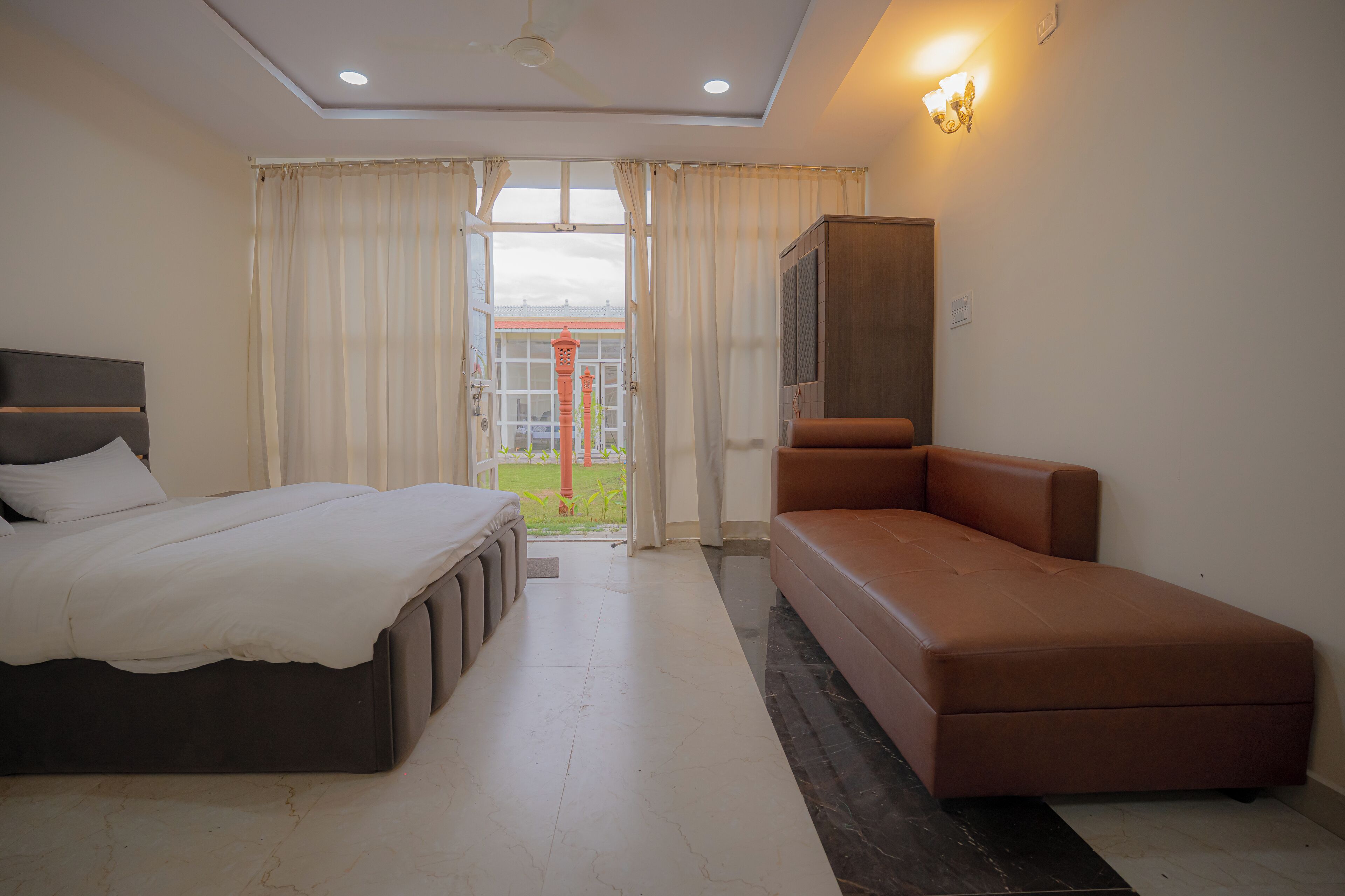 Habitación de hotel con cama, sofá, televisión y vista a un edificio.