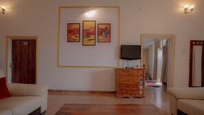 Una sala de estar con dos sofás, una mesa de centro de madera, un televisor y tres obras de arte enmarcadas en la pared.