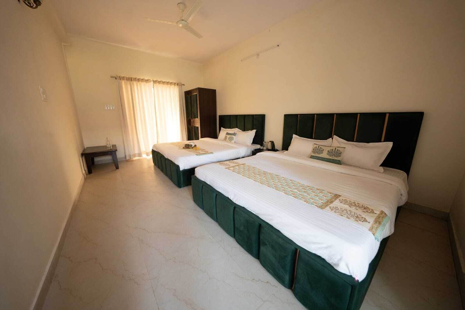 Ein Hotelzimmer mit zwei Betten, einem Schreibtisch und einem Deckenventilator.