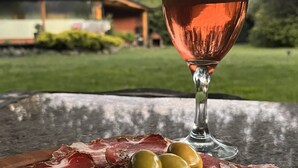 Une table avec un verre de vin rosé, des charcuteries et des olives.