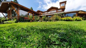 Un chalet en bois doté d’un patio couvert, entouré d’une végétation luxuriante et surplombant un ciel dégagé.