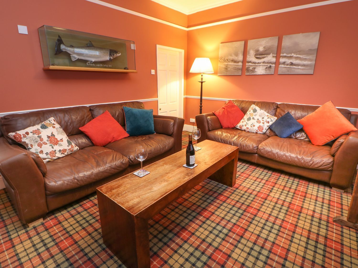 A cozy living room with two brown leather sofas, a wooden coffee table, and a patterned carpet.