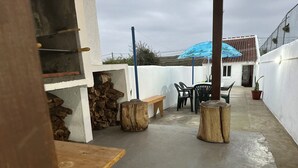 An outdoor patio area with a concrete floor, wooden benches, a table, and chairs. - Casa Santa Maria (Vila do Porto)