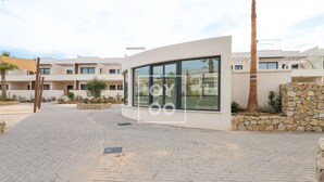 A modern building with a glass facade, a paved entrance, and a stone wall. - Amalia Garden Groundfloor Retreat, a footstep from beach and sea, By OYOOSTAYS (Torrevieja)