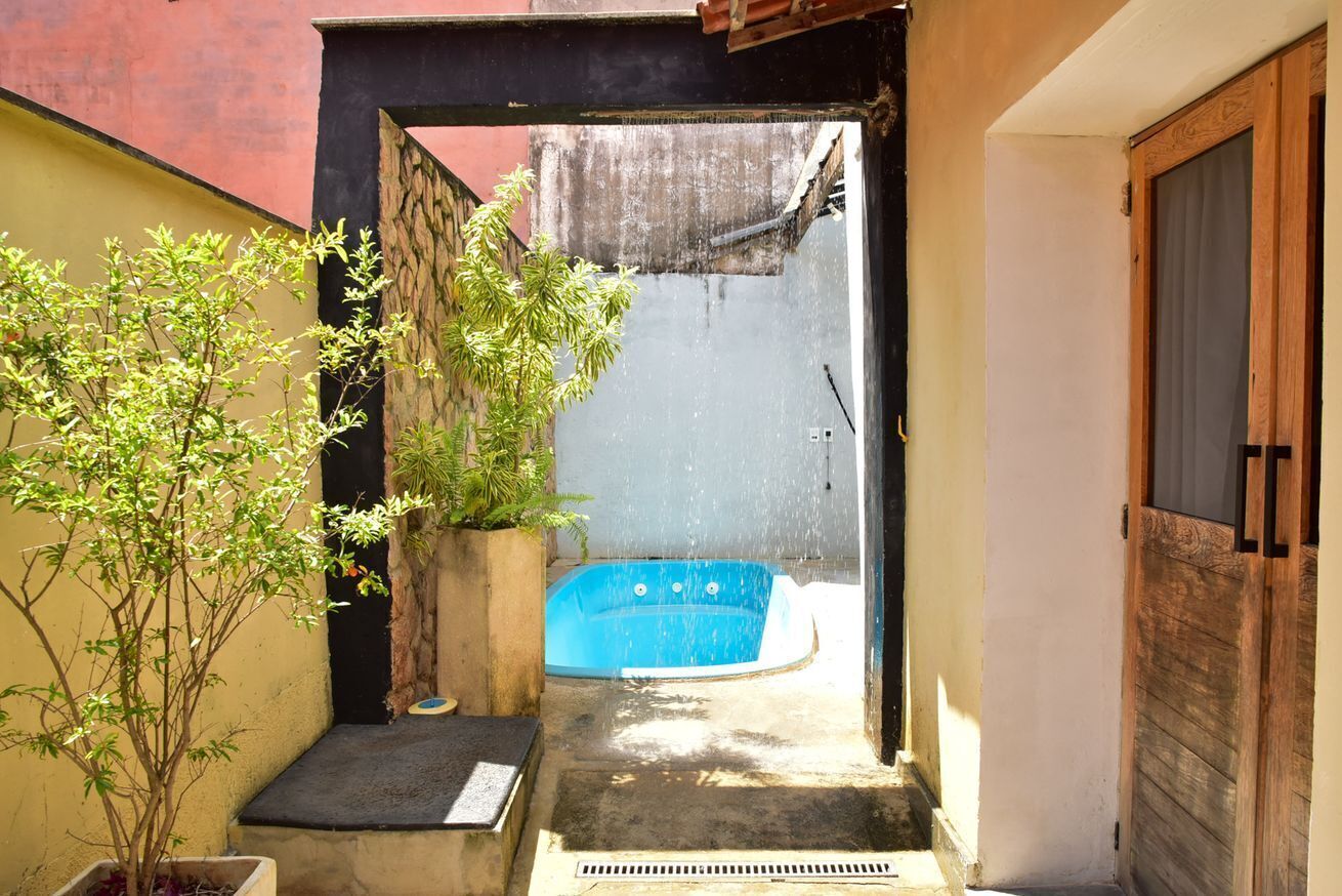 A narrow outdoor space with a blue hot tub, a small bench, and a potted plant.