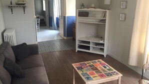 Ett vardagsrum med en soffa, ett träbord med en färgglad design, en vit hylla och ett element.
