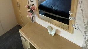 Ett sovrum med en säng, en byrå, en spegel och en vas med blommor.
