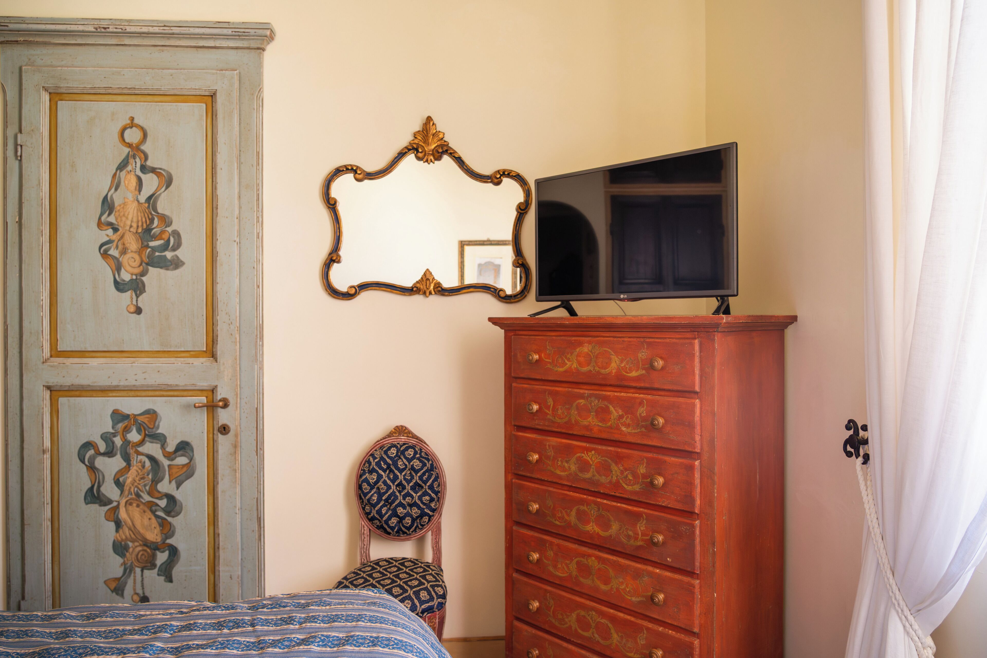 A room with a bed, a dresser, a mirror, and a television.