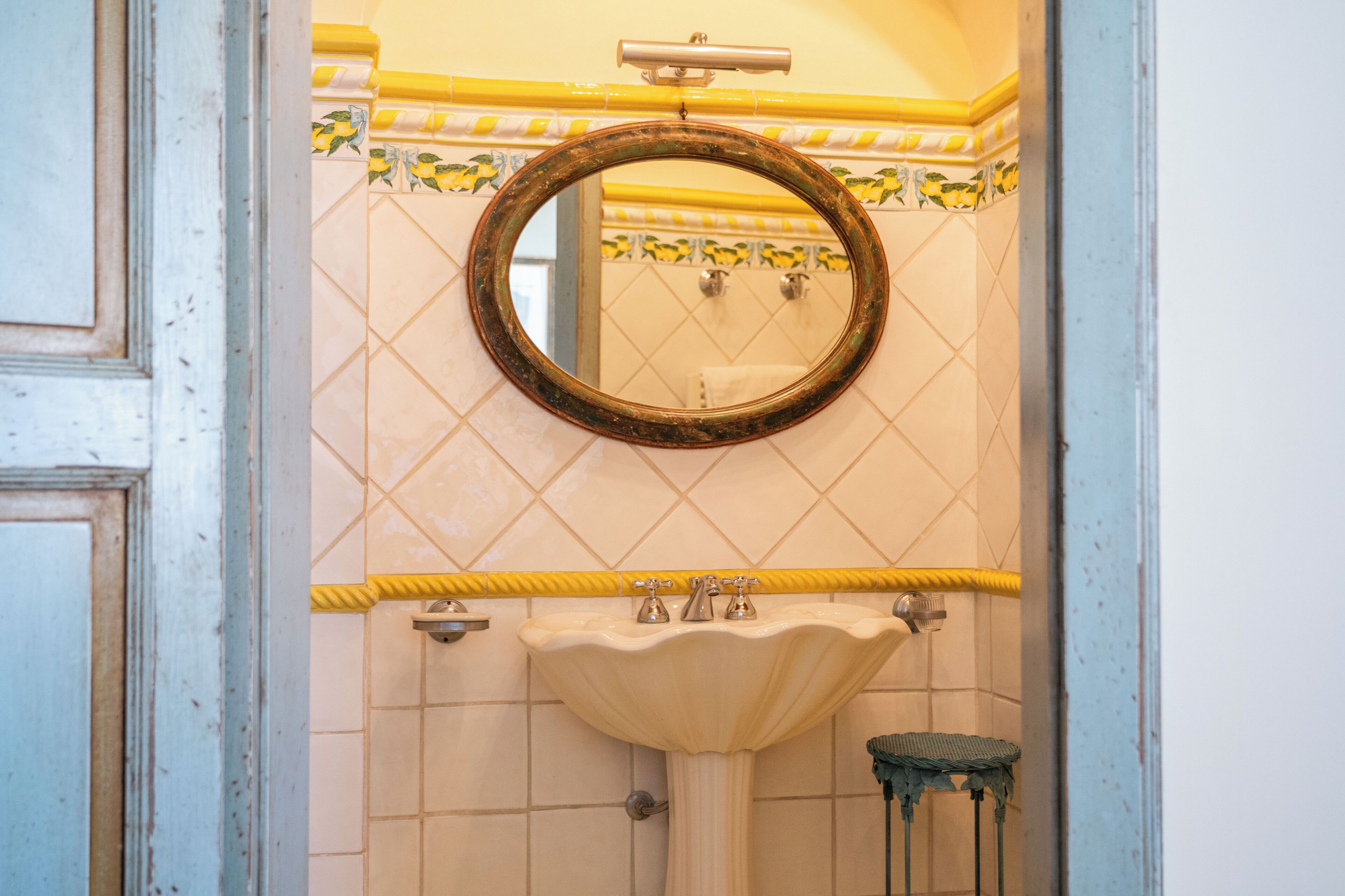 Une salle de bain avec un lavabo, un miroir et un porte-serviettes jaune.