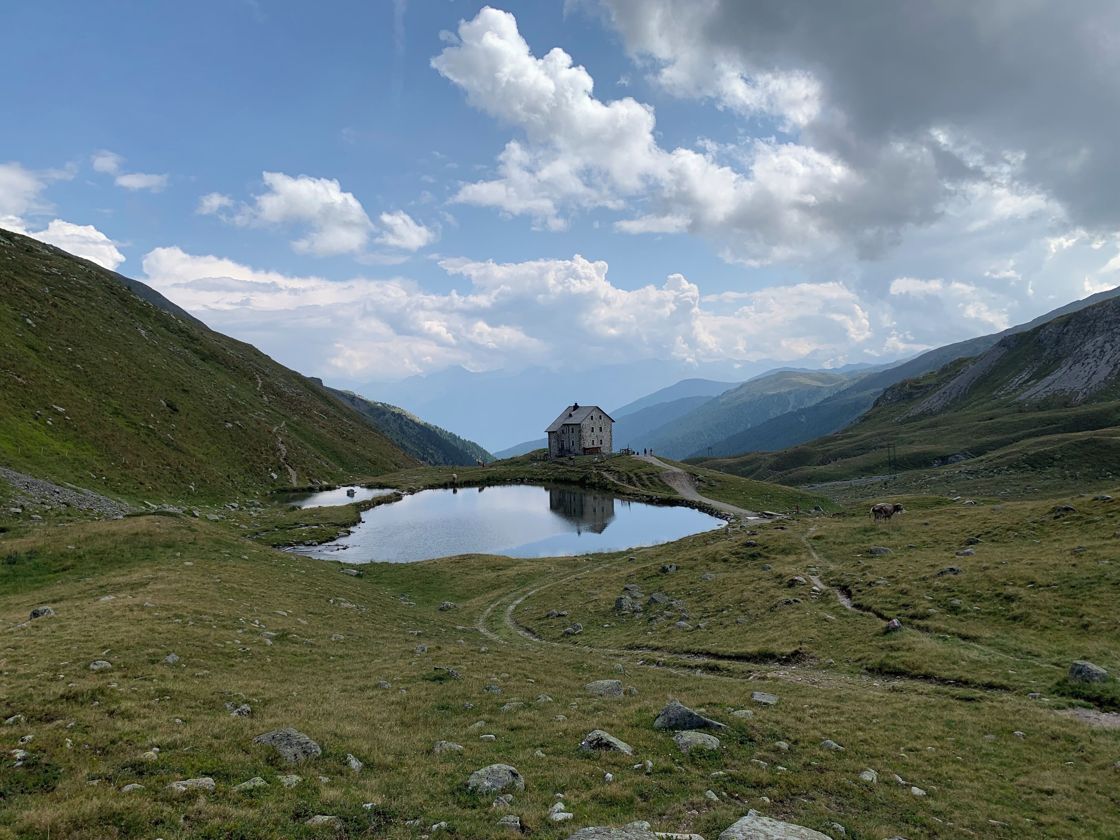 Un edificio in pietra con uno stagno in una zona montuosa.