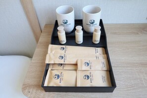 A tray with SORA HOTEL PHU GUOC branded items including two mugs, three bottles, and several toiletry packets. - Sora Hotel (Phu Quoc)