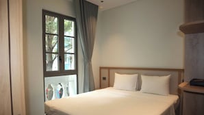 Une chambre d’hôtel avec un grand lit, une fenêtre avec des rideaux et une tête de lit en bois.
