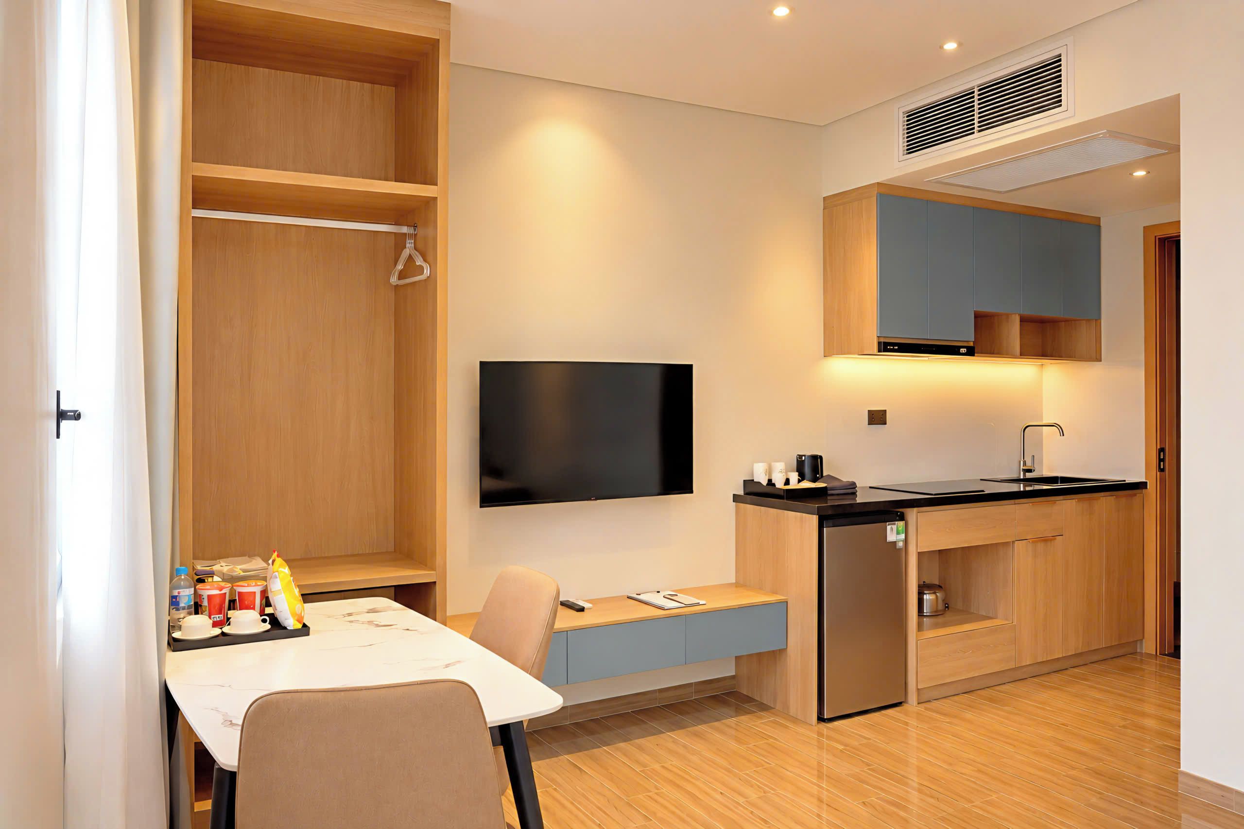 Una cocina compacta con estufa integrada, un televisor de pantalla plana y un pequeño comedor con mesa y sillas.