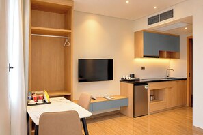 Une cuisine compacte équipée d’une cuisinière intégrée, d’un téléviseur à écran plat et d’un petit coin repas avec une table et des chaises.