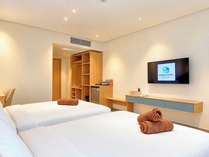 Une chambre d’hôtel avec deux lits, une télévision, un bureau et une armoire.