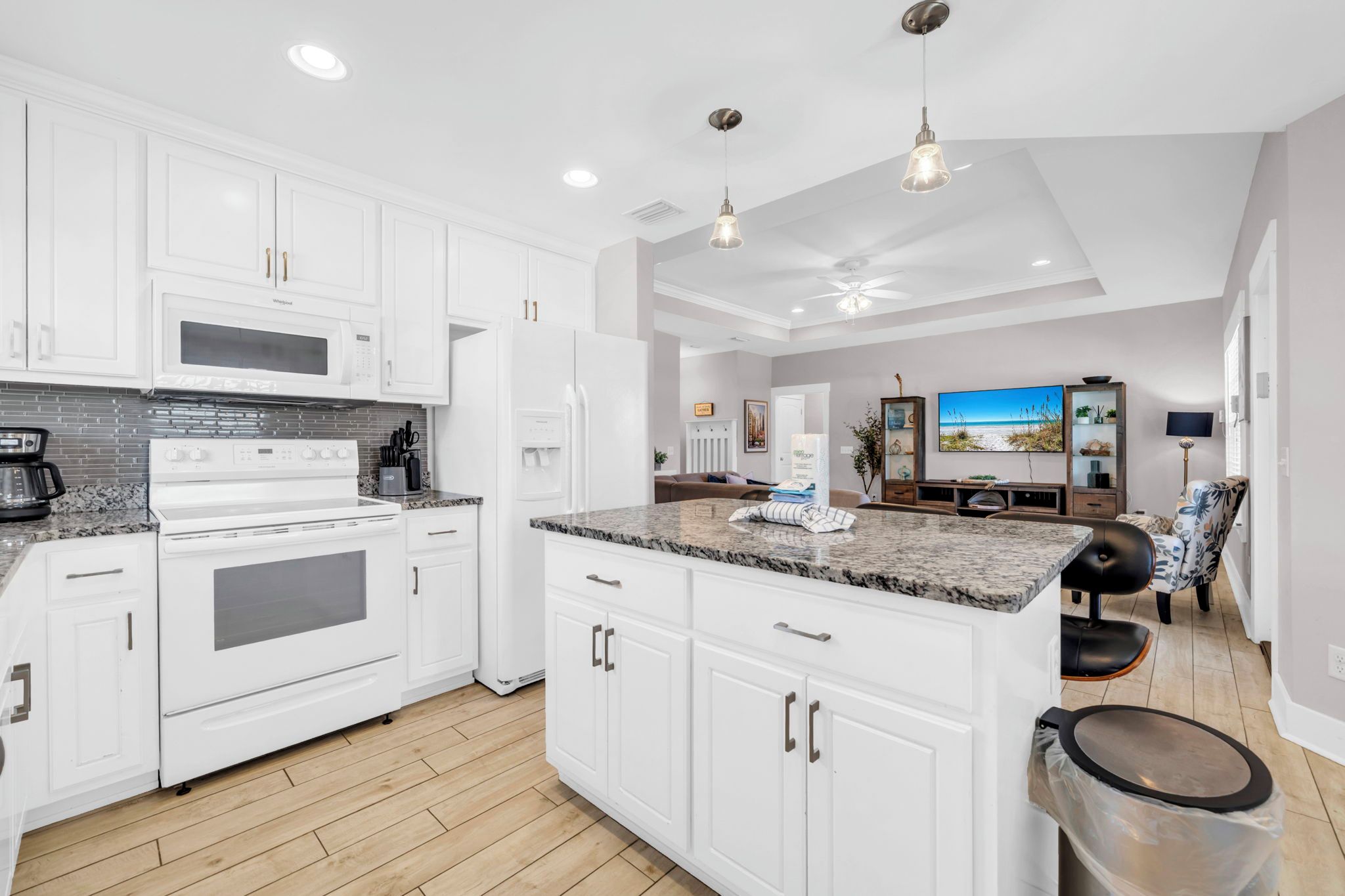 A modern kitchen with white cabinetry, a built-in oven, and a granite countertop.