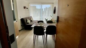 Una sala de estar moderna con comedor, ventanas amplias y vista a la ciudad.