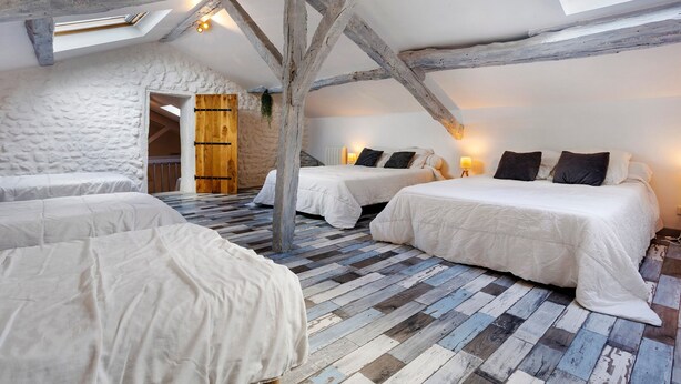 Un dormitorio rústico con vigas de madera a la vista, techo inclinado y piso a cuadros.