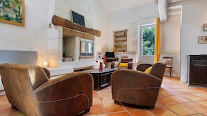 Una sala de estar con chimenea, dos sillones de cuero, una mesa de centro y un televisor.