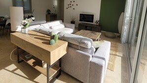 Uma sala de estar moderna com um sofá, uma mesa de centro de madeira e uma televisão.