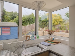 A kitchen with a large window, a metal drying rack, and a sink. - 20 Lym Close (Lyme Regis)