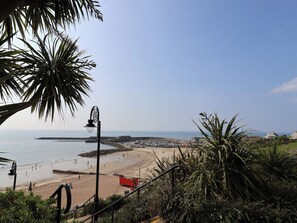Une scène de plage côtière offrant une vue dégagée sur la mer, une plage de sable et un promontoire rocheux situé au loin.
