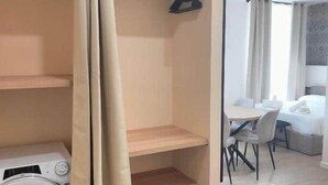Une pièce équipée d’un lave-linge, d’un coin repas avec une table et des chaises, et d’un lit.