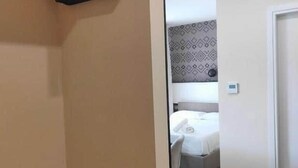 Une chambre à coucher avec un lit, une table de chevet, une armoire suspendue et un mur décoré d’un motif.