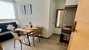 Um espaço compacto com área de jantar, cozinha compacta e sofá.