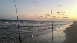 A beach with fishing rods set up along the shore. - Your Coastal Getaway:3BR/2BA Beach Retreat (Bolivar Peninsula)