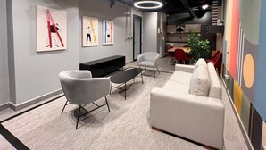 Un intérieur moderne avec un canapé, des fauteuils, une table basse et des œuvres d’art accrochées aux murs.