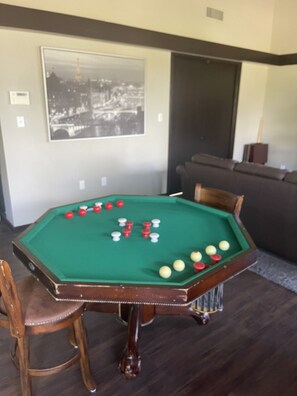 Une table de billard avec des billes, un tableau encadré au mur et un canapé à l’arrière-plan.