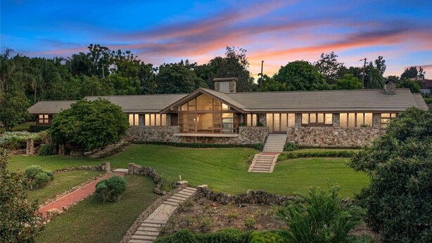 A modern house with a stone facade, large windows, and a well-maintained lawn.