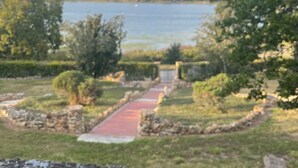 A pathway leading to a body of water, surrounded by greenery and stone structures.